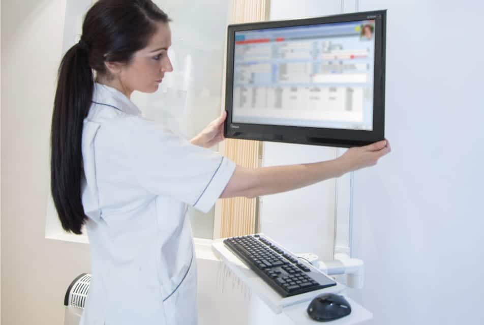 Nurse adjusting a wall mounted monitor