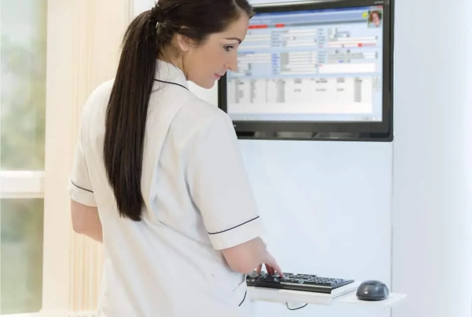 Nurse updating patient records on a wall mounted monitor