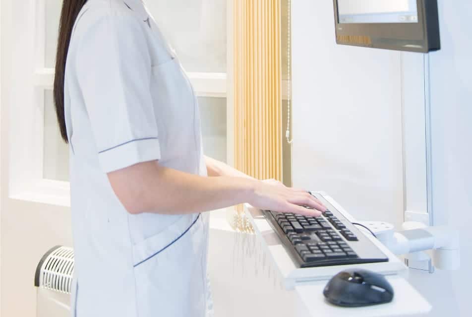 Nurse using a computer with a wall mounted monitor