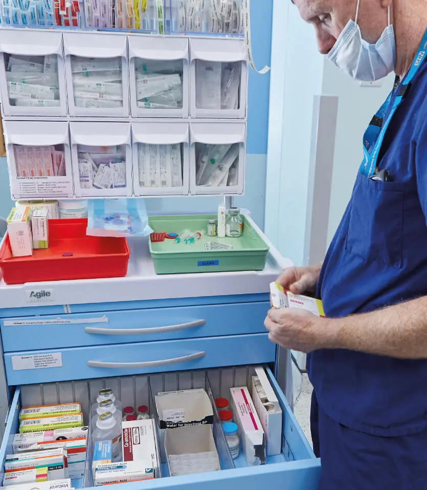 A medical professional utilising an Agile Medical LX Anaesthetic Trolley in light blue